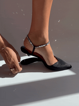 Black pointed-toe slingback pump with jeweled ankle strap and sculpted heel on foot