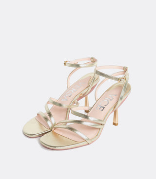 gold high-heeled sandals with ankle straps and visible brand text VICE VERSA