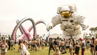 Crowd at a festival with a large inflatable astronaut and colorful looping sculpture