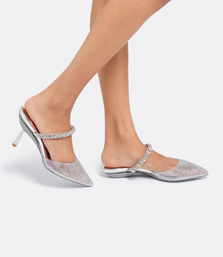 Model walking in the VICE VERSA Isadora Mules in clear crystal, one in heel mode and one folded flat