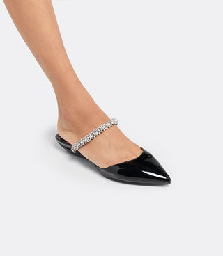 Model wearing the VICE VERSA Isadora Mule in black patent folded into a flat
