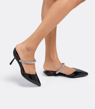 Model walking in the VICE VERSA Isadora Mules in black patent, one in heel mode and one folded flat
