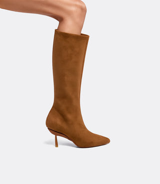 Side view of a model wearing the VICE VERSA Knee High Boots in walnut faux suede in heel mode