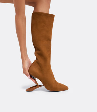 Model folding the heel of the VICE VERSA Knee High Boots in walnut faux suede to convert it to a flat