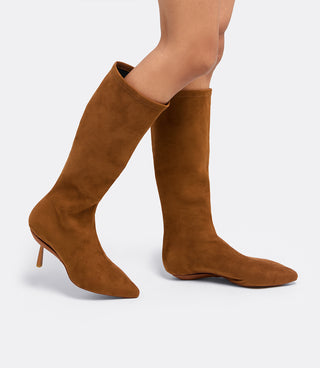 Model walking in the VICE VERSA Knee High Boots in walnut faux suede, one in heel mode and one folded flat