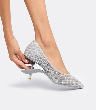 Model folding the heel of the VICE VERSA Ella Pump in silver crystal mesh to convert it to a flat