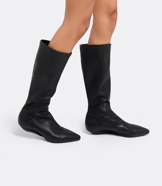Model wearing the VICE VERSA Knee High Boots in black faux leather folded into flats