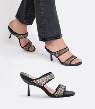Black high-heeled sandals with crystal mesh material worn by a person on a white background
