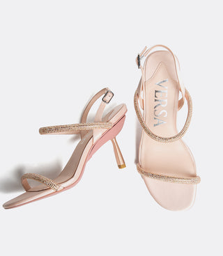 Pair of rose gold high-heeled sandals with 'VICE VERSA' branding on a light gray background