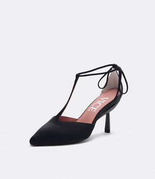 A single black pointed-toe high heel pump with a thin T-strap and ankle tie, shown on a light gray background. The insole is pink with the brand name 'VICE' printed in white.