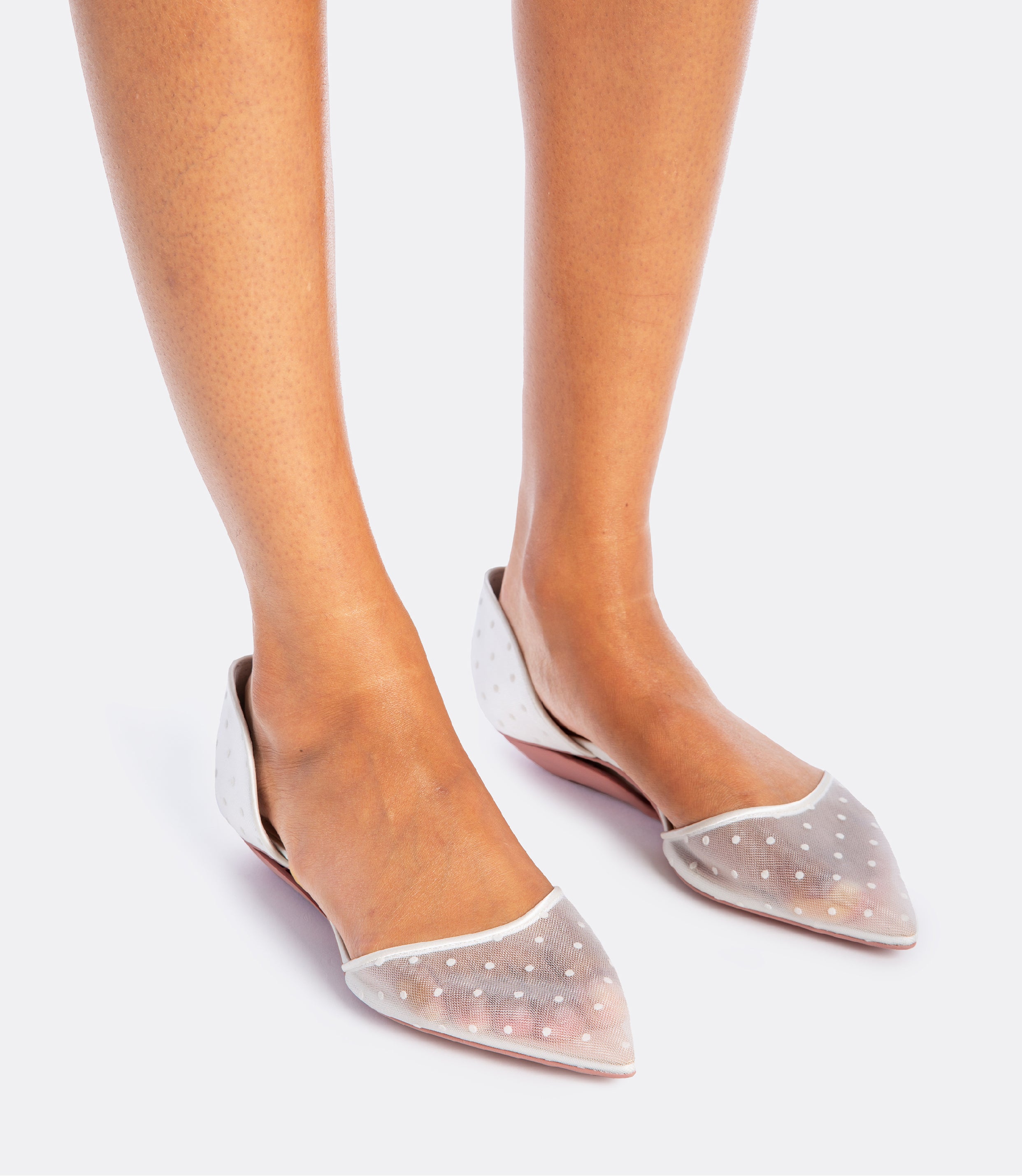 Model wearing a white polka dot mesh heel as a flat