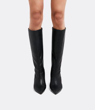 Front view of a model wearing the VICE VERSA Knee High Boots in black faux leather with pointed toes