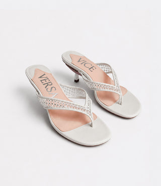 White high-heeled sandals with clear straps and pink insole on a light gray background
