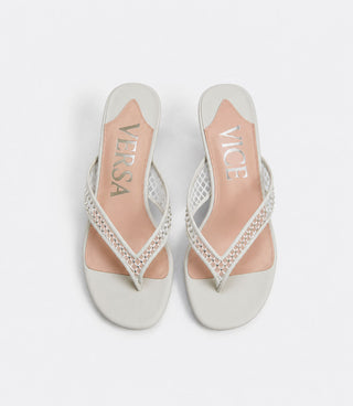 White sandals with embellishments on a light gray background
