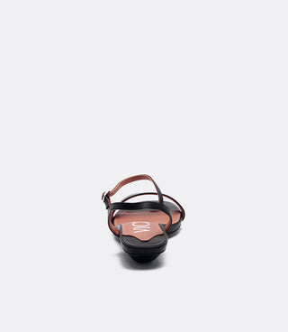 A single black leather flat sandal with a thin ankle strap and a low wedge heel, shown from the back on a white background.